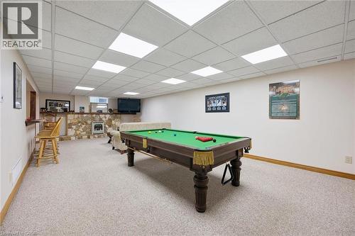 Spacious entertainment area featuring a drop ceiling with integrated lighting, a stone-clad hearth, a built-in bar, and neutral Berber carpeting - 410 Avenue Road, Cambridge, ON - Indoor Photo Showing Other Room
