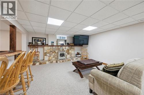 Finished lower level featuring a stone-faced bar with a built-in fireplace, a live-edge wooden bar top, wood-finish support posts, and recessed ceiling lighting - 410 Avenue Road, Cambridge, ON - Indoor