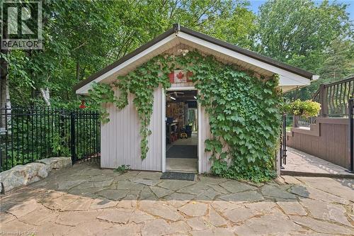 Freestanding outbuilding featuring an ivy-clad facade, a pitched roofline, and a stone slab patio - 410 Avenue Road, Cambridge, ON - Outdoor