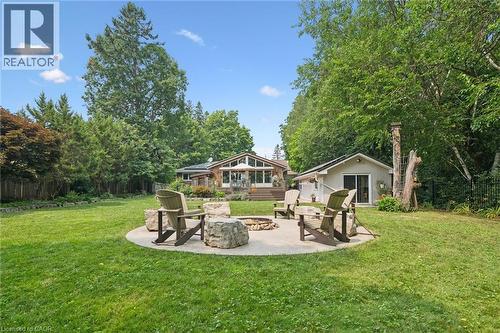Expansive green lawn featuring a circular patio fire pit with stone seating - 410 Avenue Road, Cambridge, ON - Outdoor