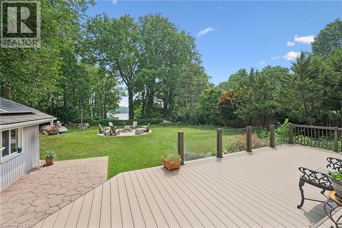 Expansive composite deck overlooking a manicured lawn with fire pit area overlooking a lake - 410 Avenue Road, Cambridge, ON - Outdoor With Backyard