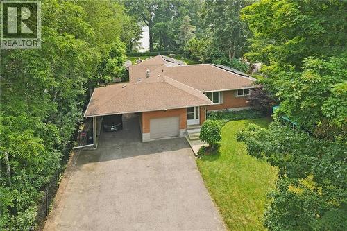 Brick residence featuring a covered carport, attached garage, and a sloped shingled roof with solar panels - 410 Avenue Road, Cambridge, ON - Outdoor