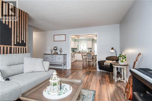 Living space featuring wood-finish flooring, a decorative accent wall with vertical wood paneling, and light gray painted walls - 67 Pinemeadow Crescent, Waterloo, ON - Indoor Photo Showing Living Room
