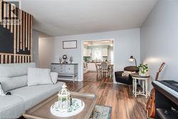 Living space featuring wood-finish flooring, a decorative accent wall with vertical wood paneling, and light gray painted walls - 