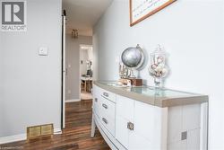 Hallway featuring wood-finish flooring, a contemporary white dresser with a light-toned top, and a sliding barn-style door - 