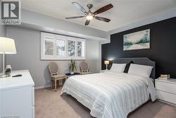 Bedroom featuring a ceiling fan with integrated lighting, a dark accent wall, and a window with plantation shutters - 