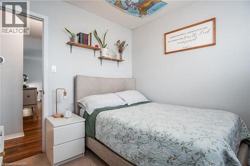 Carpeted bedroom featuring a neutral color palette, a visible doorway to a wood-finish floor, and built-in wall shelves - 67 Pinemeadow Crescent, Waterloo, ON - Indoor Photo Showing Bedroom
