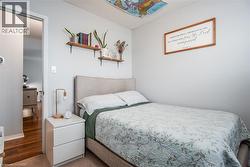 Carpeted bedroom featuring a neutral color palette, a visible doorway to a wood-finish floor, and built-in wall shelves - 