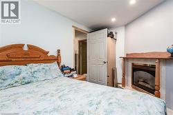 Bedroom featuring a wood headboard, light blue painted walls, recessed lighting, and a fireplace with a wood mantel - 