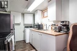 Compact kitchenette featuring white cabinetry, light wood-finish countertops, and a single basin sink - 