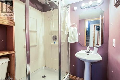 Three-piece bathroom featuring a pedestal sink with chrome faucet, octagonal mirror, and vanity lighting - 67 Pinemeadow Crescent, Waterloo, ON - Indoor Photo Showing Bathroom