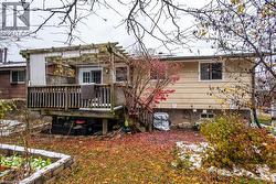 Rear exterior featuring a raised wooden deck with a pergola, sliding glass door access, and beige siding - 