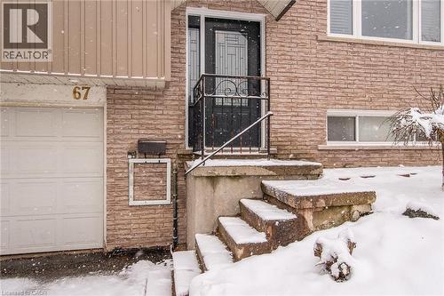 Brick facade with a white garage door, concrete steps, and a black wrought iron handrail - 67 Pinemeadow Crescent, Waterloo, ON - Outdoor With Exterior