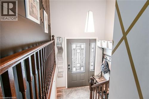 Foyer with a paneled entry door featuring decorative glass and coordinating sidelights, a two-story ceiling, a contemporary pendant light fixture, and a built-in coat rack with shelving - 67 Pinemeadow Crescent, Waterloo, ON - Indoor Photo Showing Other Room