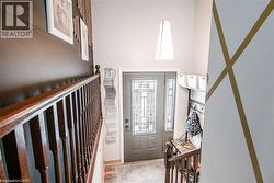 Foyer with a paneled entry door featuring decorative glass and coordinating sidelights, a two-story ceiling, a contemporary pendant light fixture, and a built-in coat rack with shelving - 