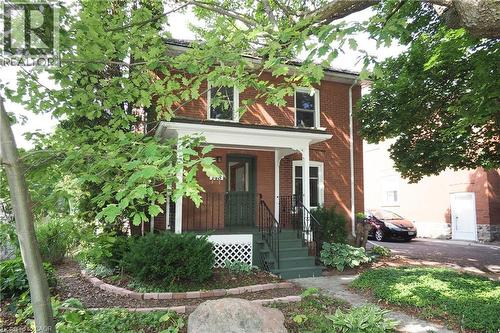 Brick exterior featuring a covered porch with white columns, dark green steps, and black wrought iron railings - 148 Tiffany Street, Cambridge, ON - Outdoor