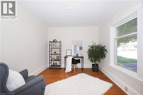 Room featuring wood-finish flooring, white baseboards, crown molding, and a large window with white trim - 148 Tiffany Street, Cambridge, ON - Indoor