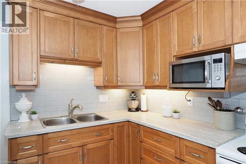 Light wood-finish cabinetry, subway tile backsplash, dual basin stainless steel sink, under-cabinet lighting, and light-toned countertops - 148 Tiffany Street, Cambridge, ON - Indoor Photo Showing Kitchen With Double Sink