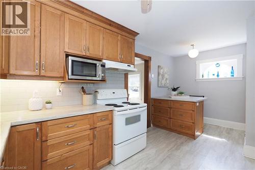Kitchen featuring wood-finish cabinetry, light-toned countertops, a white subway tile backsplash, and wood-finish flooring - 148 Tiffany Street, Cambridge, ON - Indoor Photo Showing Kitchen