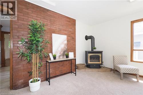 Exposed brick accent wall featuring a black wood-burning stove with a gold-tone firebox - 148 Tiffany Street, Cambridge, ON - Indoor With Fireplace