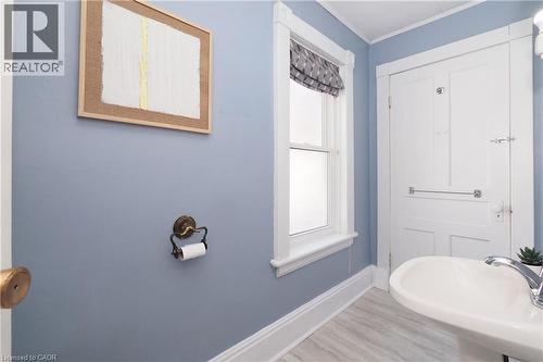 Pedestal sink with chrome faucet, light-toned wood-finish flooring, and white trim work - 148 Tiffany Street, Cambridge, ON - Indoor Photo Showing Bathroom