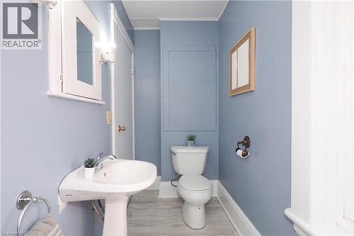 Pedestal sink with chrome faucet, white toilet, wall-mounted medicine cabinet with mirror, and light wood-finish flooring - 148 Tiffany Street, Cambridge, ON - Indoor Photo Showing Bathroom