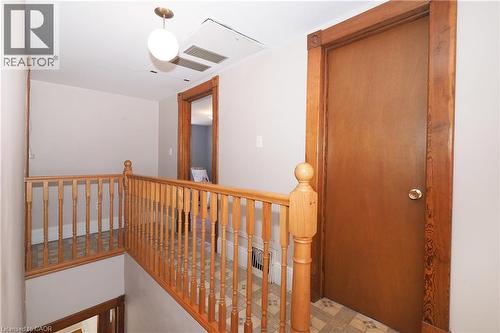 Upper landing featuring wood-finish railings, a brass-finish ceiling light fixture, wood-trimmed doorways, and patterned flooring - 148 Tiffany Street, Cambridge, ON - Indoor Photo Showing Other Room