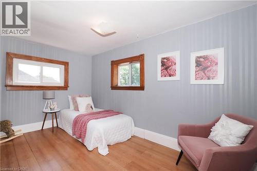 Room featuring wood-finish flooring, two windows with natural wood trim, and a ceiling-mounted light fixture - 148 Tiffany Street, Cambridge, ON - Indoor Photo Showing Bedroom