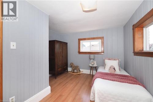 Room featuring wood-finish flooring, light blue striped walls, and a ceiling-mounted light fixture - 148 Tiffany Street, Cambridge, ON - Indoor Photo Showing Bedroom
