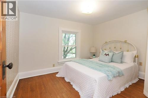 Hardwood flooring throughout featuring white baseboards, a single window with white trim, and a ceiling-mounted light fixture - 148 Tiffany Street, Cambridge, ON - Indoor Photo Showing Bedroom