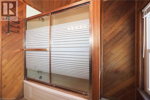 Bathtub with sliding shower doors featuring horizontal frosted privacy stripes - 148 Tiffany Street, Cambridge, ON - Indoor Photo Showing Bathroom