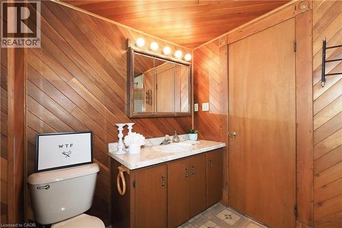 Bathroom featuring diagonal wood-panel walls and ceiling, a built-in vanity with a white countertop and integrated sink, a mirrored medicine cabinet with overhead lighting, and patterned flooring - 148 Tiffany Street, Cambridge, ON - Indoor Photo Showing Bathroom
