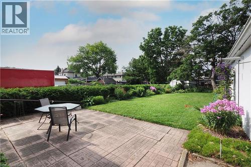 Spacious rear yard featuring a paved patio area, expansive lawn, mature perimeter landscaping, and vibrant floral plantings - 148 Tiffany Street, Cambridge, ON - Outdoor