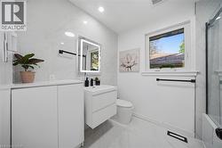 Modern bathroom featuring a floating vanity with integrated sink, illuminated mirror, and a window providing natural light - 
