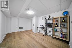 Spacious room featuring wood-finish flooring, white walls, and a drop ceiling with recessed lighting - 