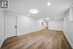 Spacious room featuring wood-finish flooring, recessed lighting, and a white paneled door with black hardware - 