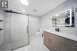 Modern bathroom featuring a glass-enclosed shower, white tile flooring, and a single vanity with an integrated sink - 