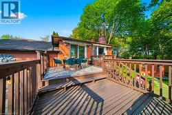 Multi-level wood-finish deck featuring a built-in railing system, direct access to the interior via sliding glass doors, and an awning over the lower section - 