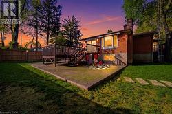 Rear exterior featuring a brick facade, multi-level wood deck, ground-level paver patio, and a grassy yard with stepping stones - 