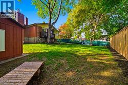 Spacious backyard featuring a wooden privacy fence, mature trees, and a red-sided shed - 