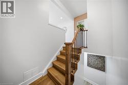 Staircase with wood-finish treads and risers, featuring a wood handrail with black metal balusters - 