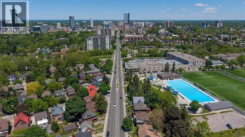 Aerial perspective showcasing a property surrounded by mature trees, with a prominent street and urban skyline in the background - 744 Queen Street S, Kitchener, ON - Outdoor With View
