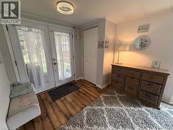 Entryway featuring wood-finish flooring, a contemporary ceiling light fixture, a double glass-panel door, and a built-in storage closet - 