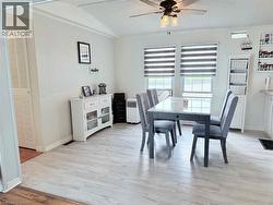Bright dining area featuring wood-finish flooring, a contemporary ceiling fan with integrated lighting, and two large windows with horizontal blinds - 