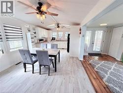 Open-concept living area with light wood-finish flooring extending into the dining space - 