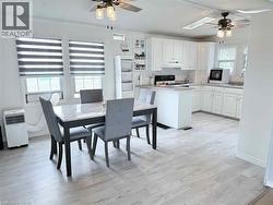 Open-concept kitchen and dining area featuring light wood-finish flooring, white cabinetry, and a central island - 