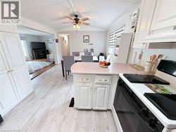 Kitchen featuring white cabinetry with gold-tone hardware, a white range, and light wood-finish flooring - 