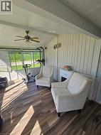 Enclosed sunroom featuring wood-finish flooring, a vaulted ceiling with a ceiling fan, and white paneling - 