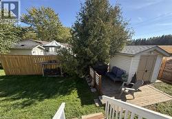 Expansive backyard featuring a wood privacy fence, a storage shed with shingle roofing, and a wood deck - 