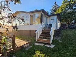 Exterior featuring a sunroom with large windows, a wooden deck, and a multi-level porch with white railings - 